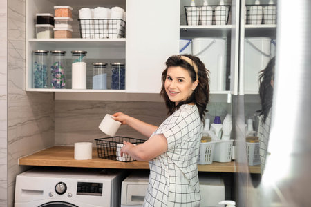 Woman organizing white bathroom laundry comfortable storage on cupboard shelvesの写真素材