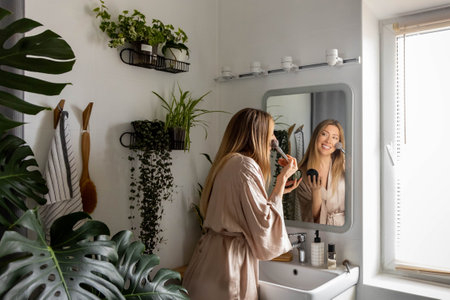 A young beautiful woman combs her long hair and takes care of her skin in the morning at homeの写真素材