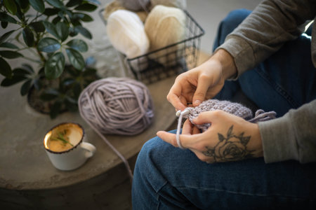 Male hands crochet handmade artwork use wool yarn and hook over table with coffee top viewの写真素材