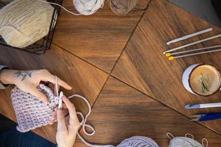 Feminine male hands crochet handmade artwork hobby wooden table with sewing tools closeup top viewの写真素材