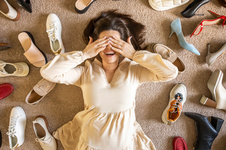 Modern woman surrounded by abstract shoes lying on beige carpet floor shopping consumerism top viewの写真素材