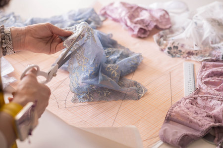 A woman seamstress designs and draws a pattern for underwear on graph paper. Various patterns