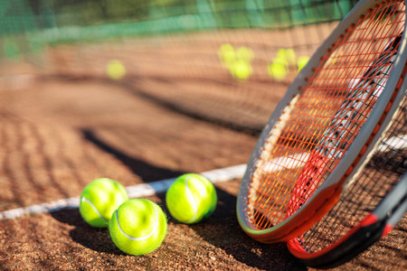 Tennis ball with rocket near grid at outdoor summer sunny court closeupの写真素材