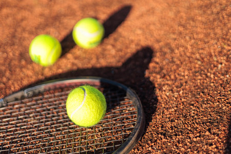Tennis ball with rocket near grid at outdoor summer sunny court closeupの写真素材