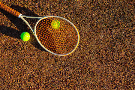 Yellow tennis ball lying on rocket at outdoor summer sunny court ground closeup