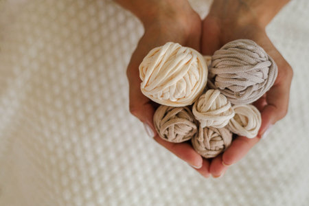 Womens hands hold balls and skeins of cotton yarn in the shape of a heart.の写真素材