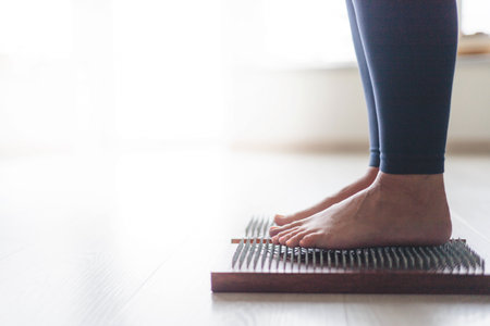 Yoga woman legs standing on nails with singing meditation bowl top view closeupの写真素材