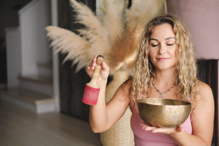 Yoga woman with singing meditation bowl enjoy sound with closed eyes closeupの写真素材
