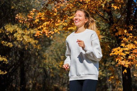 Young beautiful girl jogging in city beautiful autumn park and forest enjoy outdoor sports.の写真素材