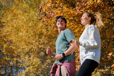 Sporty family couple morning jogging in city autumn beautiful park. Young active mans runnersの写真素材
