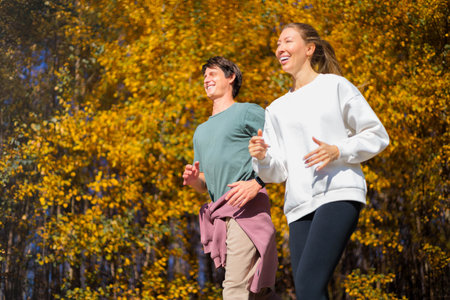 Young couple jogging in city beautiful autumn park and forest, enjoying outdoor sports