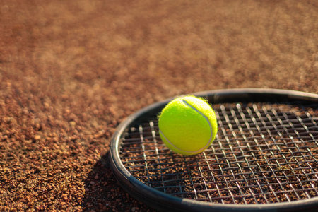 Yellow tennis ball lying on rocket at outdoor summer sunny court ground closeupの写真素材