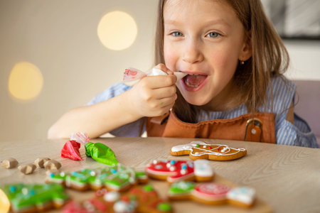 A little girl decorates a Christmas gingerbread mitten. Concept of preparations for Christmas