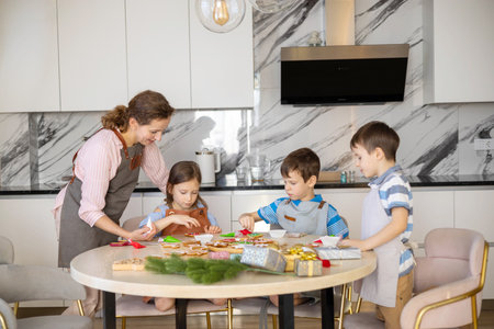 Happy family mother and children in aprons making Christmas cookies together while cookingの写真素材