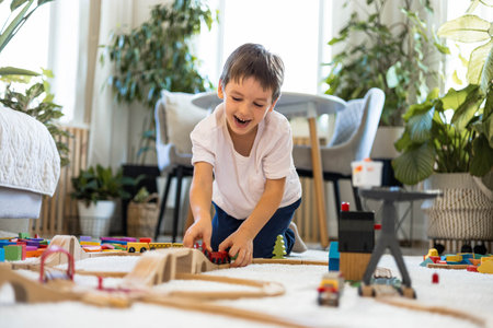 A European child plays with a wooden railway and colored blocks at home. The boy builds a cityの写真素材