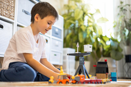 A cute little boy builds a city and a railroad from wooden blocks. He plays with trainsの写真素材