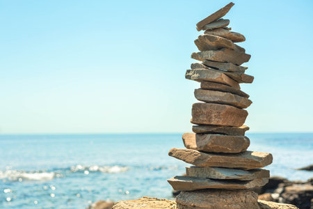 Stone tower at sunny sea coast beach balance harmony zen symbol. Natural pebble pyramidの写真素材
