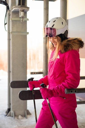 Attractive happy woman model in pink overalls with skis.の写真素材