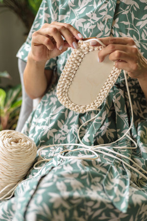 Womens hands crochet a storage basket from white and beige yarn. Concept of womens hobby