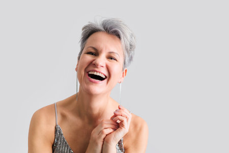 Beautiful happy middle-aged woman with gray short hair smiling and looking at camera.の写真素材