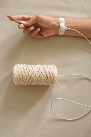 Concept of knitting, womens hobby and leisure. A womans hand is connected with a wire to a skein