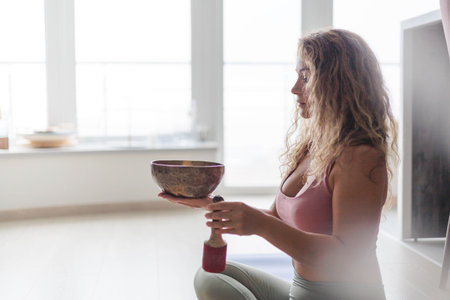 Yoga woman with singing meditation bowl enjoy sound with closed eyes closeupの写真素材