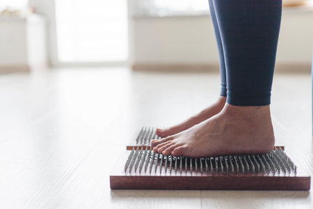 Yoga woman legs standing on nails with singing meditation bowl top view closeupの写真素材