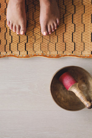 Yoga woman legs standing on nails with meditation bowl top view closeupの写真素材