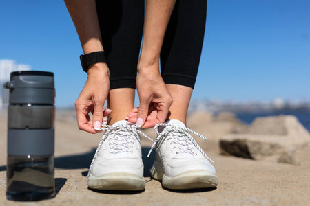 Woman runner jogger hands tying shoelace on sneakers enjoy outdoor activity closeupの写真素材