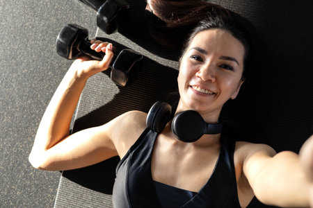 Strong beautiful fitness woman training back doing exercise with dumbbells at gym.の写真素材