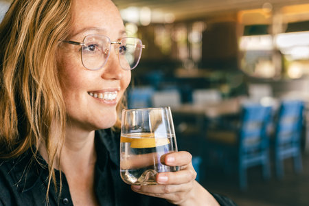 Happy Woman Drinking Water in Cafe, Healthy Lifestyle and Refreshment, Natural Light Close-Upの写真素材