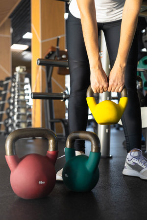 Athletic bodybuilding sport woman squat with kettlebell fitness training at gym.の写真素材