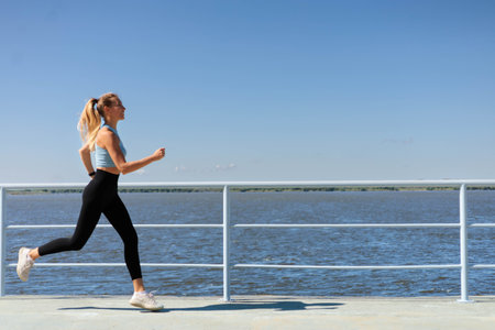 Sport woman morning running jogging on city river embankment side view