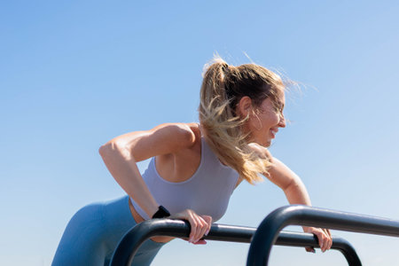 Fitness woman doing push ups from bar training at outdoor summer park closeupの写真素材