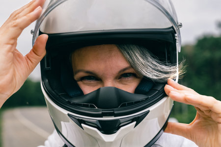 Close-up of mature woman in helmet with gray hair, symbol of confidence, freedom and timeless beautyの写真素材