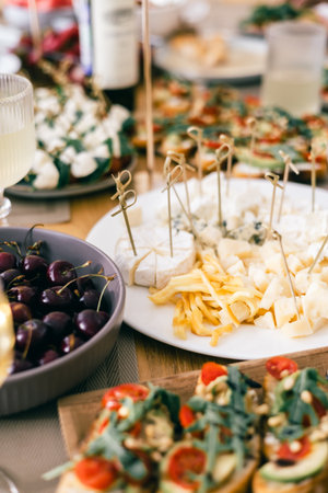 Cheese platter with cherries and bruschetta on festive table during summer lunch, wine tasting eventの写真素材