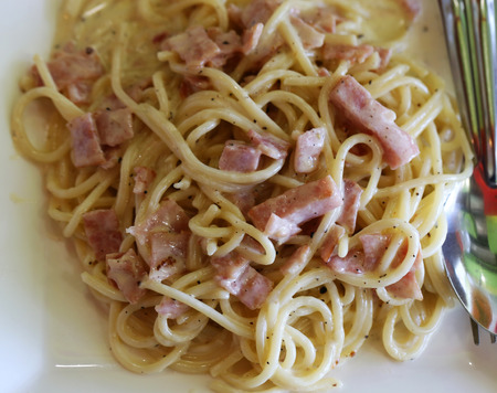 Spaghetti with ham photographed closeup on a white plateの写真素材