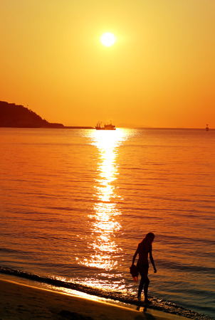 Silhouette of girl on a background sunset by the seaの写真素材