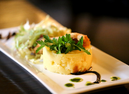 Tasty potatoes with chicken schnitzel and greens on a white plateの写真素材