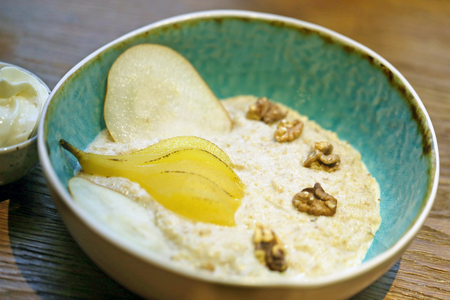 Oatmeal with pear and walnuts on almond milkの写真素材