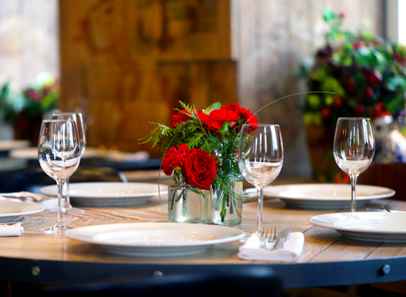 Beautiful table in the restaurant with appliances, glasses and red roses in a vase