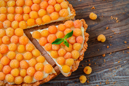 Delicious raspberry tarts on a wooden boardの写真素材