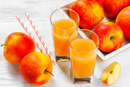 Glass of apple juice with apples on white wood backgroundの写真素材