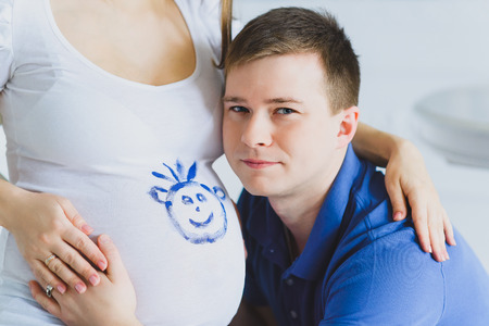 happy man listening the belly of his pregnant wifeの写真素材