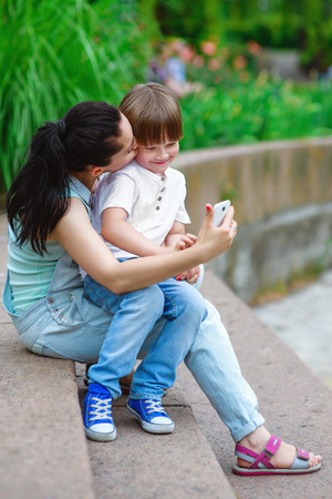 Loving mother kiss son and taking self portrait  at parkの写真素材