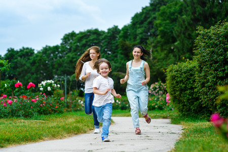 Happy Mother with daughter and son running on grass smiling.の写真素材