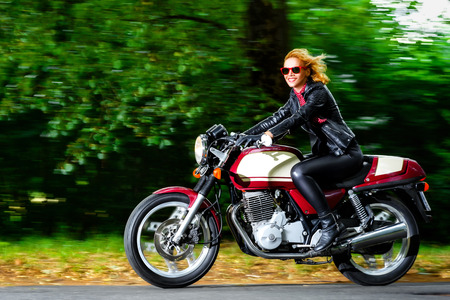 Active woman riding on the motorbike, slow motion, having fun in bikers tour, vintage style photo, happy adventure conceptの写真素材