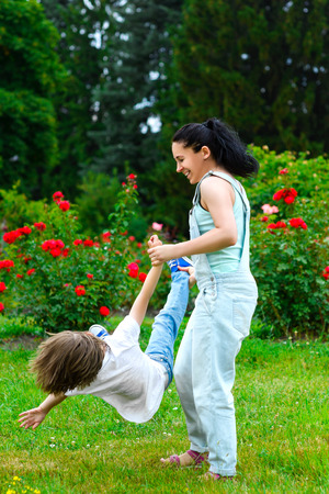 Happy mother and son spinning in summer park.の写真素材