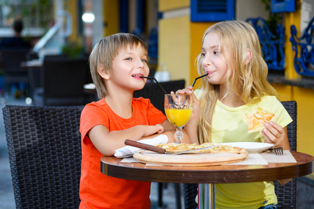 Happy or satisfied boy width girl eating pizza and drinking juice.の写真素材
