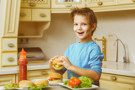 smiling happy boy holding homemade hamburgers and sandwiches.の写真素材